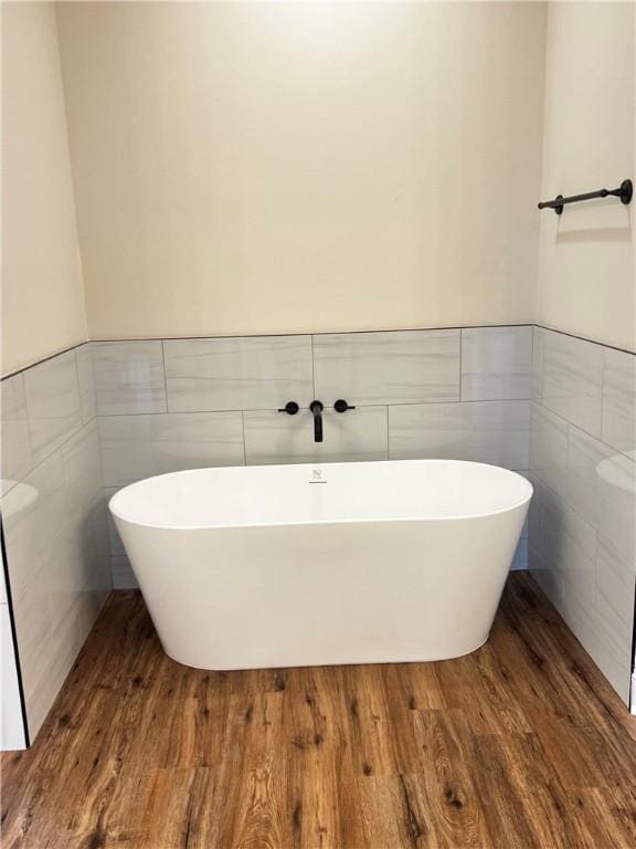 bathroom with tile walls, a wainscoted wall, and a freestanding bath