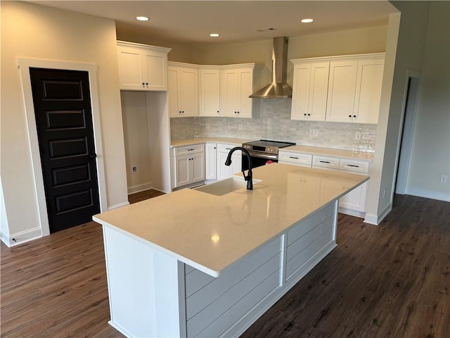 kitchen featuring a sink, wall chimney exhaust hood, stainless steel electric stove, and white cabinets