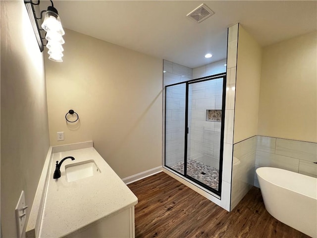 full bathroom featuring a freestanding bath, vanity, a shower stall, wood finished floors, and visible vents