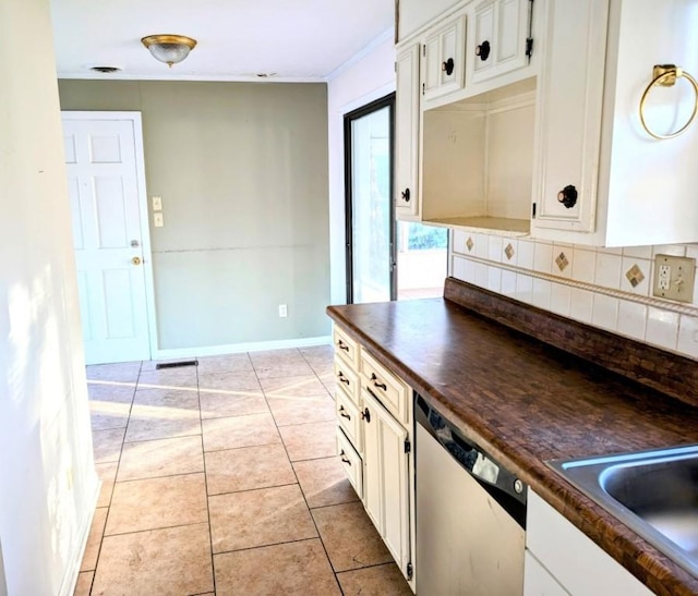 kitchen with sink, light tile patterned floors, dishwasher, white cabinets, and backsplash