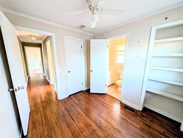 unfurnished bedroom featuring crown molding, dark hardwood / wood-style floors, ceiling fan, and ensuite bathroom