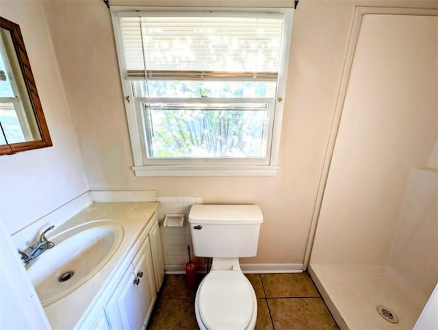 bathroom with tile patterned floors, vanity, toilet, and a shower