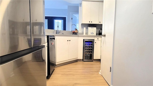 kitchen with light wood finished floors, wine cooler, white cabinetry, and freestanding refrigerator