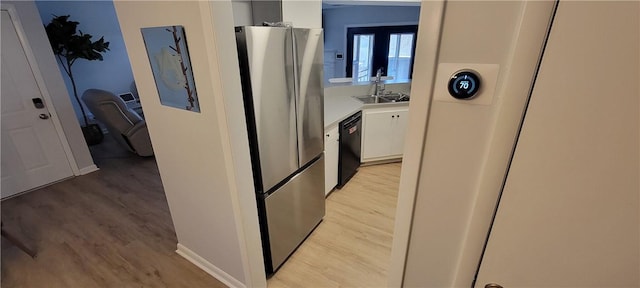 kitchen featuring a sink, white cabinets, light countertops, freestanding refrigerator, and dishwasher