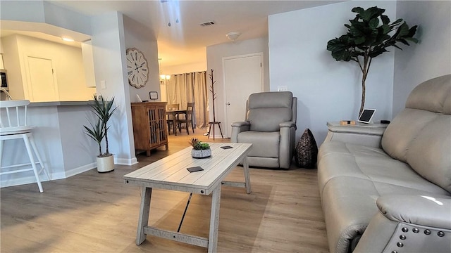 living area with light wood-style floors, visible vents, and baseboards