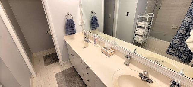 bathroom with a sink, baseboards, tiled shower / bath, tile patterned floors, and double vanity