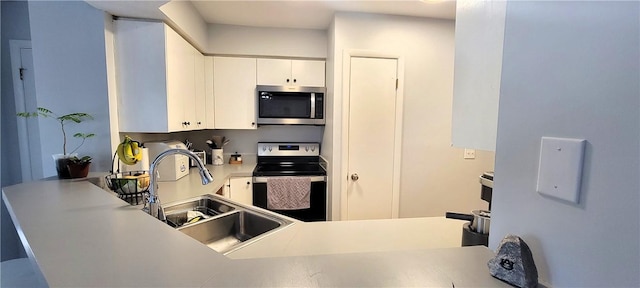 kitchen featuring white cabinets, a sink, stainless steel appliances, and light countertops