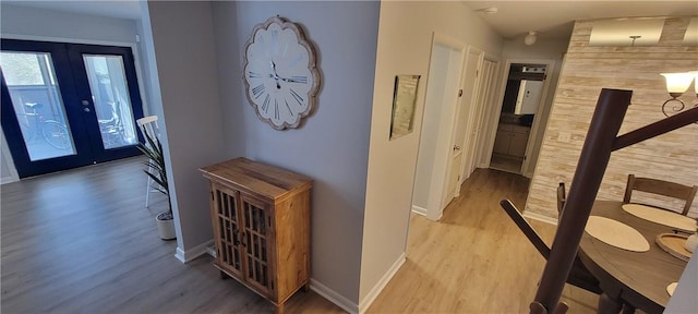hall with baseboards, french doors, and light wood-style floors