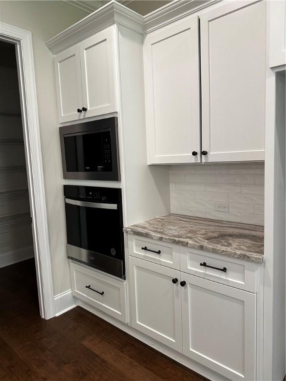 489 Windsor Dr, Opelika, AL 36801 - kitchen featuring oven, built in microwave, dark wood-type flooring, backsplash, and white cabinets
