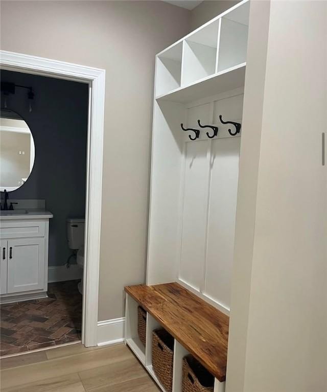 mudroom featuring a sink, light wood-style flooring, and baseboards