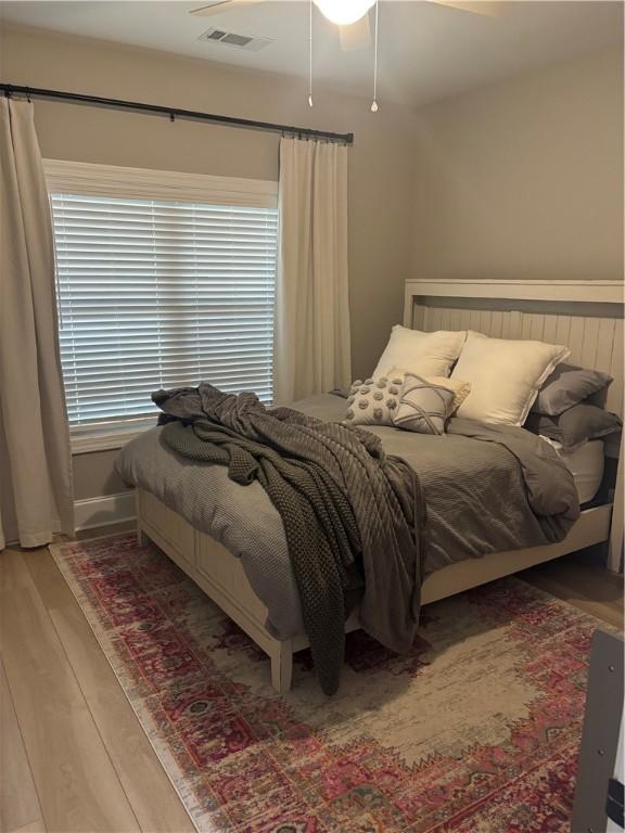 bedroom with light wood-style floors, visible vents, and a ceiling fan