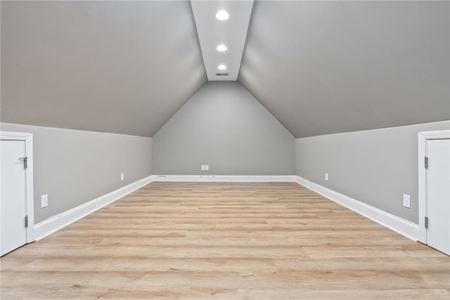 additional living space with light wood-type flooring and vaulted ceiling