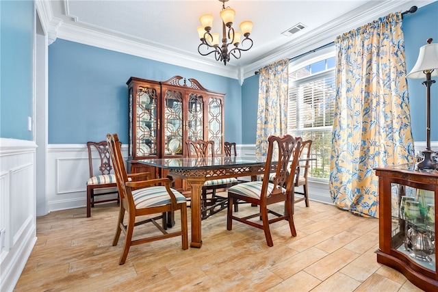 dining space featuring crown molding, light hardwood / wood-style flooring, and a chandelier