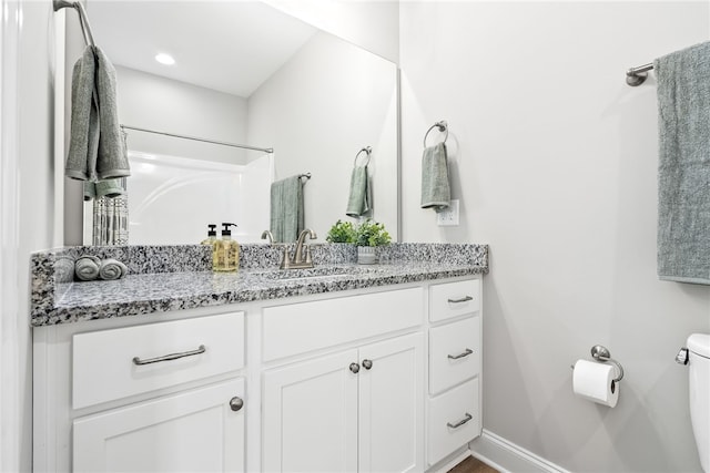 full bathroom with toilet, vanity, and baseboards