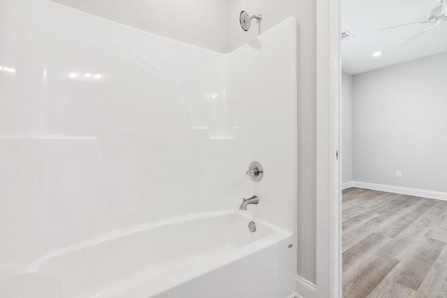 bathroom with hardwood / wood-style floors,  shower combination, and ceiling fan