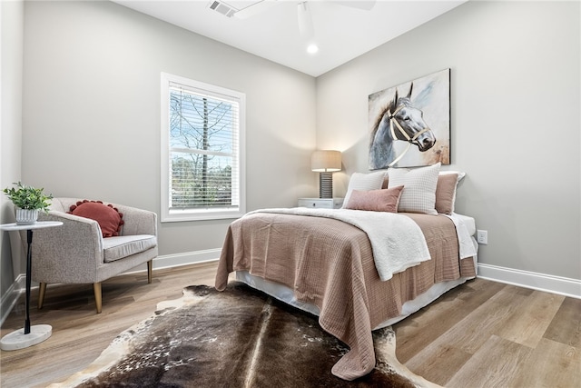 bedroom featuring baseboards, visible vents, ceiling fan, and wood finished floors