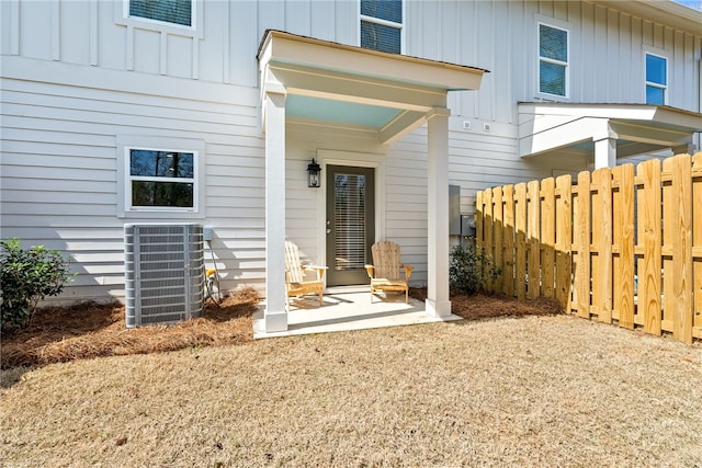 exterior space featuring central air condition unit, board and batten siding, fence, and a patio area