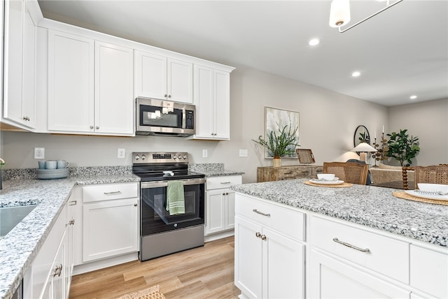 kitchen featuring recessed lighting, light wood finished floors, white cabinets, light stone countertops, and appliances with stainless steel finishes