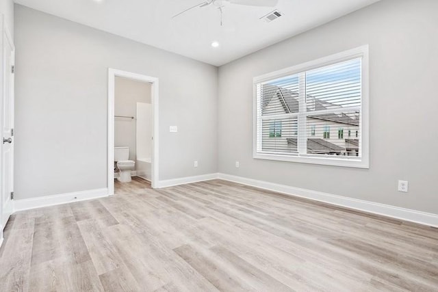 unfurnished bedroom featuring a walk in closet, connected bathroom, light hardwood / wood-style flooring, and ceiling fan