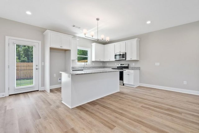 kitchen with light stone countertops, white cabinetry, a center island, stainless steel appliances, and light hardwood / wood-style floors