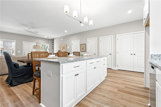kitchen featuring white cabinets, a kitchen bar, light wood-style floors, and ceiling fan