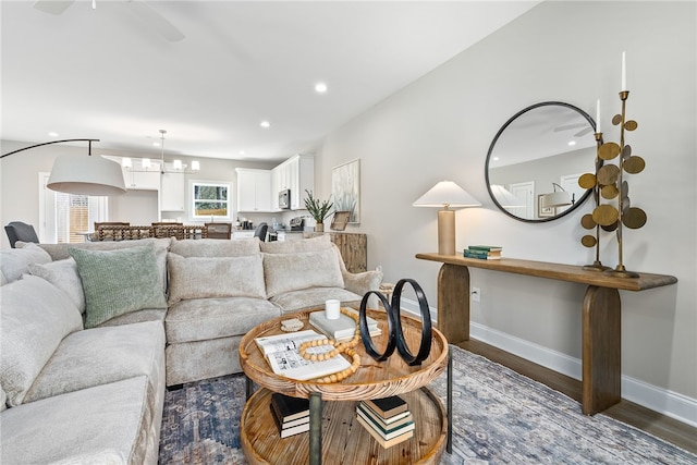 living room featuring baseboards, a notable chandelier, recessed lighting, and dark wood-type flooring