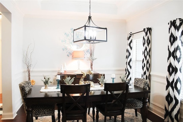 dining area with crown molding, a tray ceiling, a chandelier, and hardwood / wood-style floors