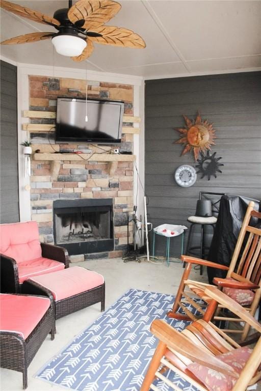 living room with ceiling fan, a fireplace, concrete flooring, and wood walls