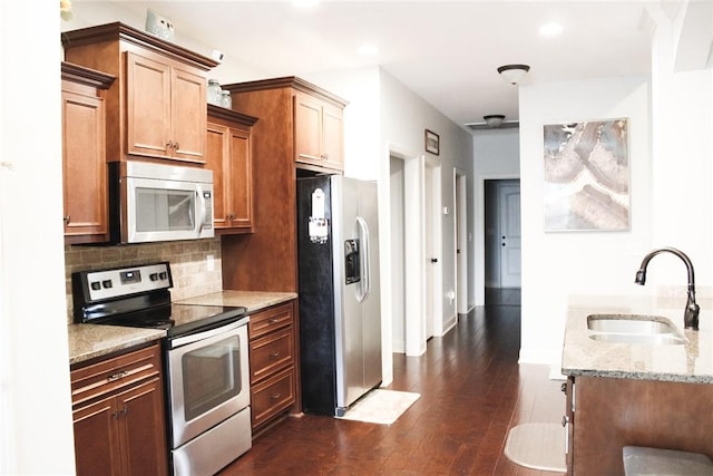 kitchen featuring dark wood-type flooring, appliances with stainless steel finishes, light stone countertops, and sink