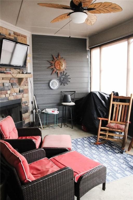 sunroom / solarium with a stone fireplace and ceiling fan