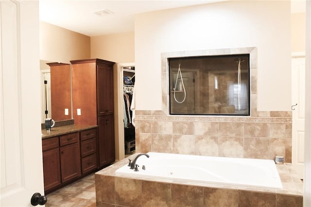 bathroom with a relaxing tiled tub and vanity