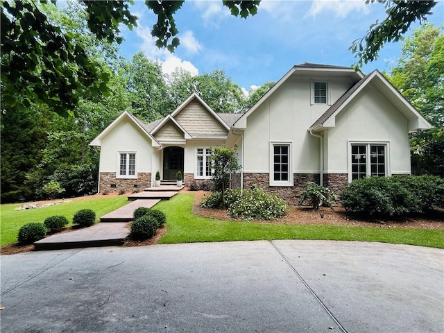 craftsman-style home with a front yard, crawl space, stone siding, and stucco siding