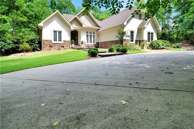 view of front facade with a front lawn, stucco siding, stone siding, and crawl space