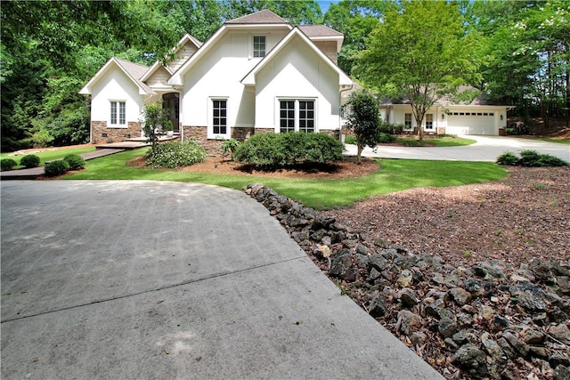 view of front of house with a front lawn, stone siding, driveway, and stucco siding