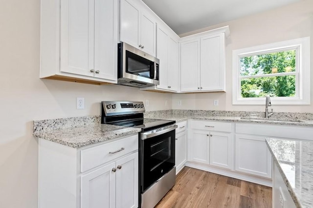 3260 Academy Dr Unit 510, Opelika, AL 36801 - kitchen featuring appliances with stainless steel finishes, a sink, white cabinetry, light wood finished floors, and light stone counters