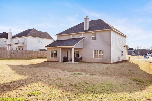 back of house featuring a yard, a shingled roof, a chimney, and fence