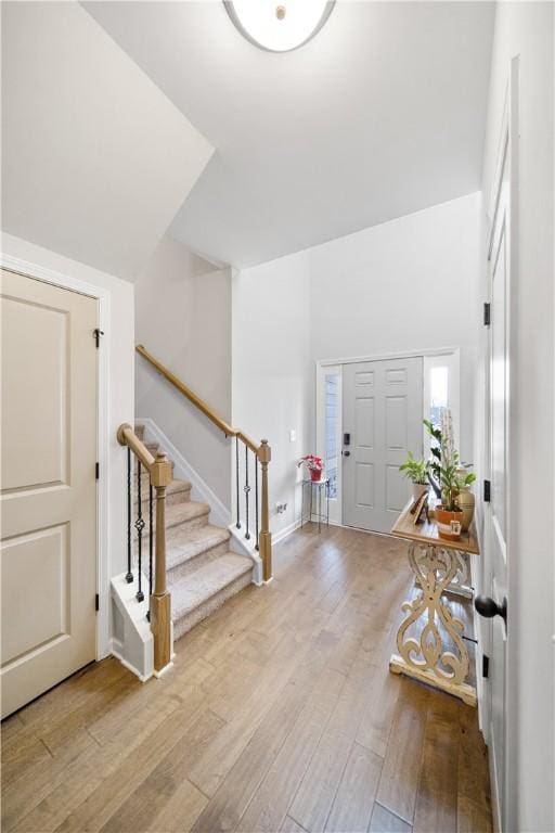 foyer featuring stairway, wood finished floors, and baseboards