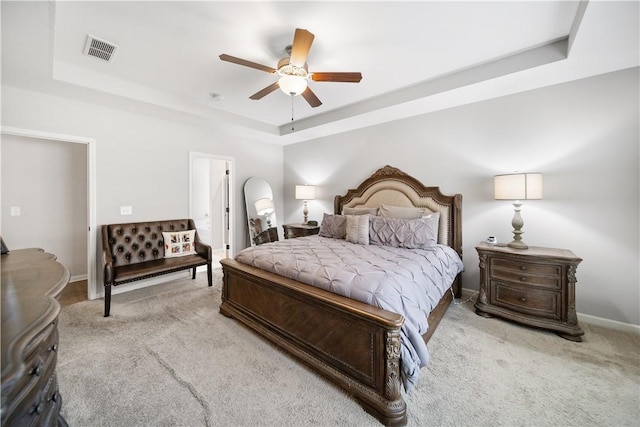 bedroom featuring baseboards, visible vents, ceiling fan, a raised ceiling, and light colored carpet