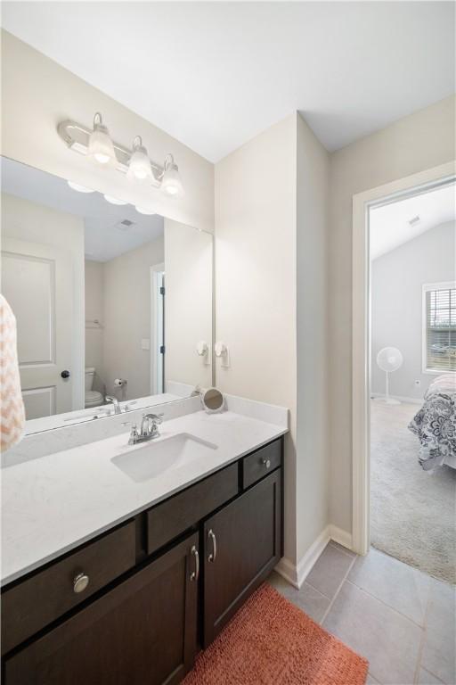 bathroom with baseboards, toilet, vanity, and tile patterned flooring