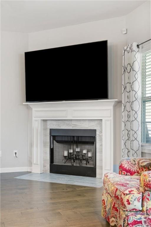 interior details with a tiled fireplace, baseboards, and wood finished floors