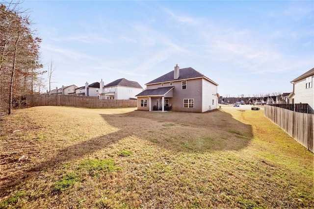 back of house featuring a chimney, a yard, and fence