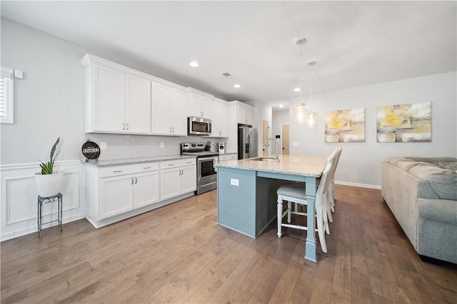 kitchen featuring white cabinetry, open floor plan, appliances with stainless steel finishes, and a sink