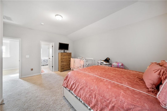 carpeted bedroom with ensuite bath, vaulted ceiling, visible vents, and baseboards