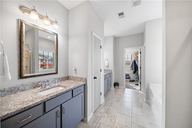 bathroom featuring a bath, visible vents, vanity, and baseboards