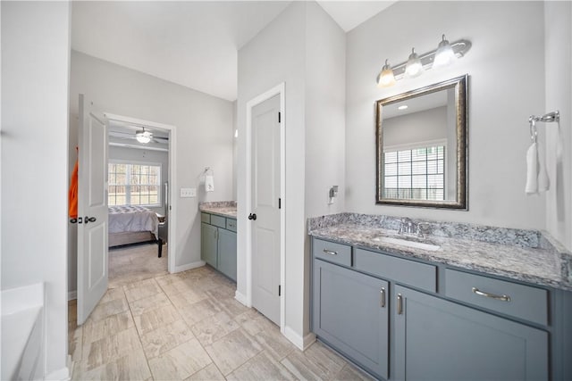 full bathroom featuring vanity, ensuite bath, and baseboards