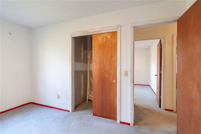 unfurnished bedroom featuring light carpet and a closet