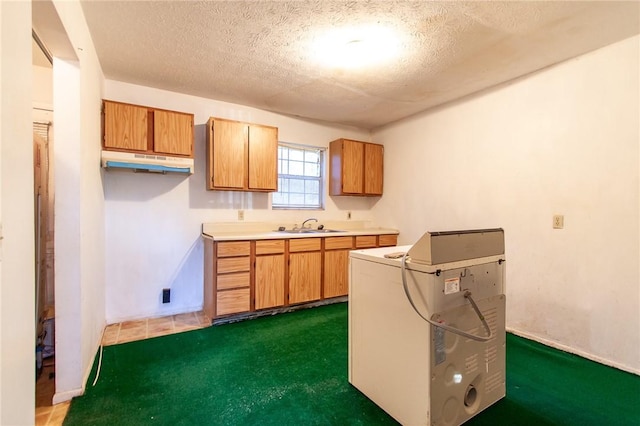 kitchen featuring dark colored carpet, sink, and a textured ceiling