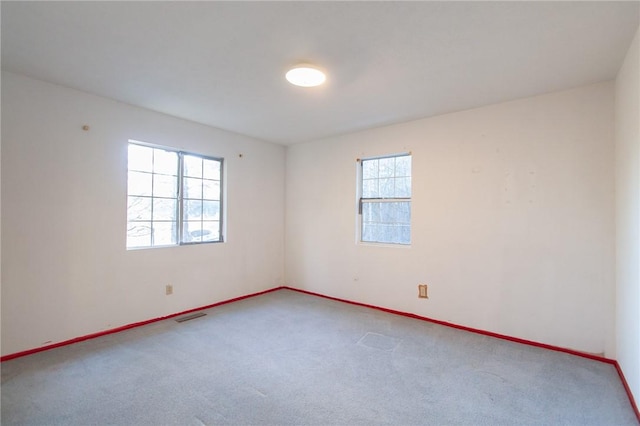 carpeted spare room featuring plenty of natural light