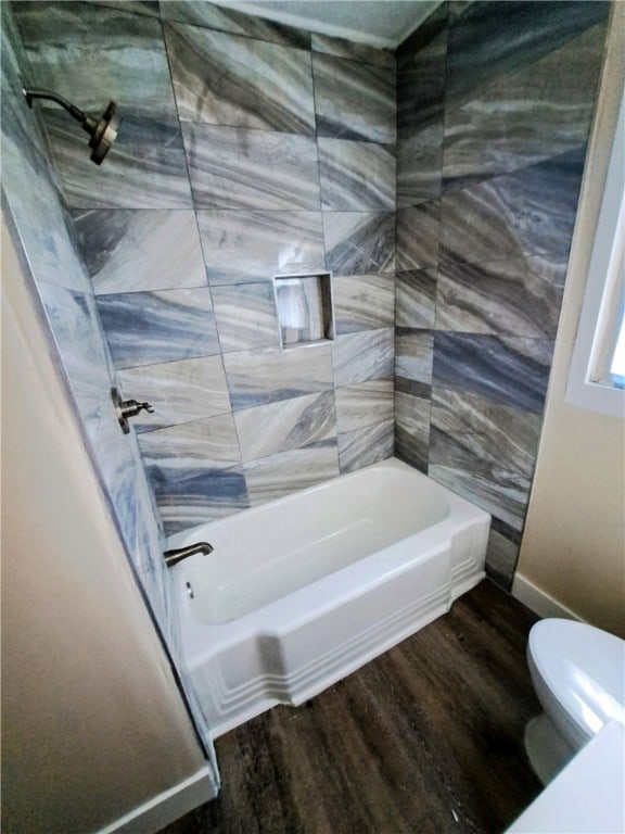 bathroom featuring hardwood / wood-style flooring, tiled shower / bath combo, and toilet