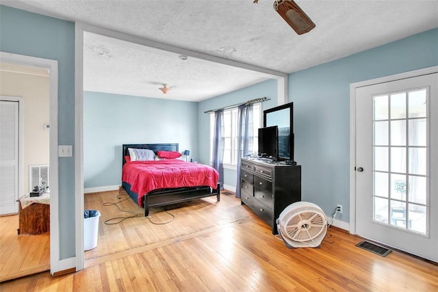 bedroom featuring ceiling fan, hardwood / wood-style floors, and a textured ceiling